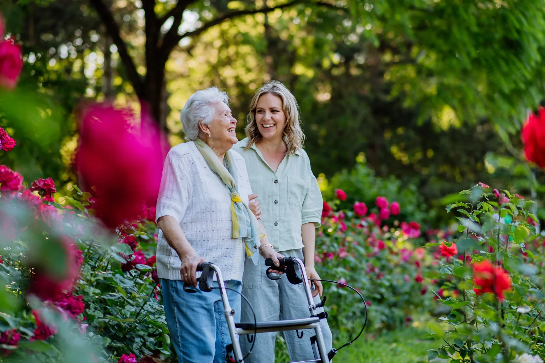 A caregiver and a senior walking together through a Northern Michigan garden