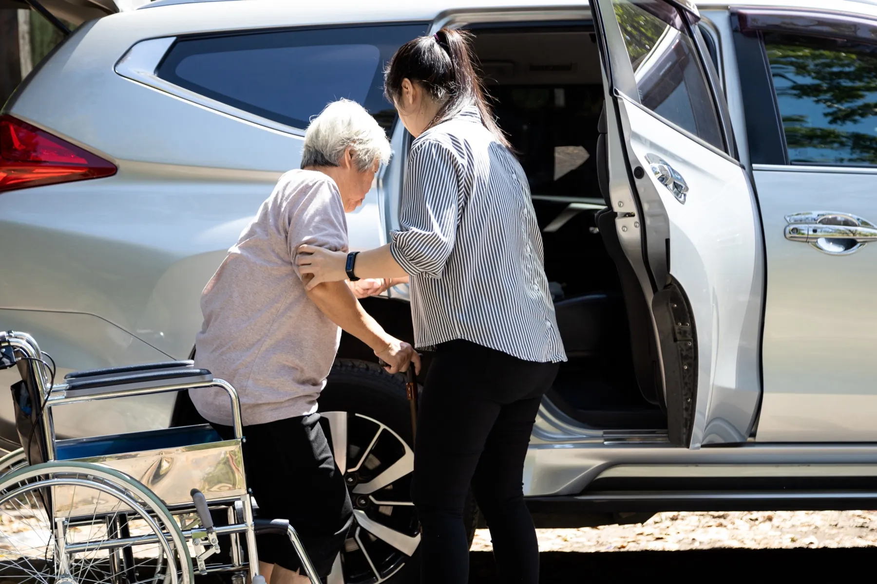 A caregiver helping a senior into the car for a ride to an appointment